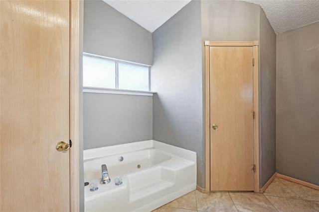 bathroom featuring tile patterned floors, vaulted ceiling, a textured ceiling, and a tub