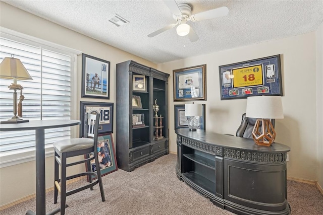 carpeted office featuring ceiling fan and a textured ceiling