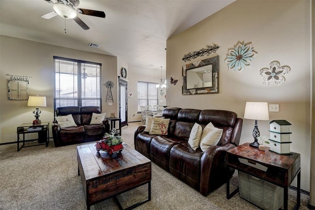 carpeted living room featuring ceiling fan with notable chandelier