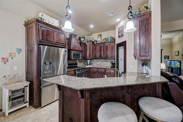 kitchen featuring light stone countertops, decorative light fixtures, stainless steel appliances, and kitchen peninsula