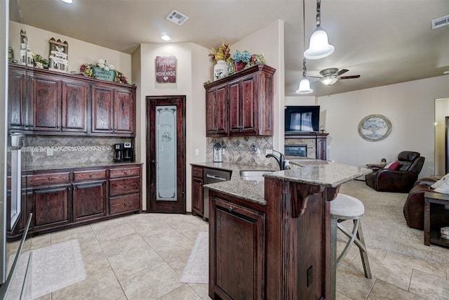 kitchen with a breakfast bar, pendant lighting, sink, kitchen peninsula, and light stone countertops