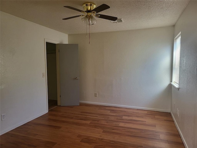 empty room featuring hardwood / wood-style flooring, a textured ceiling, and ceiling fan