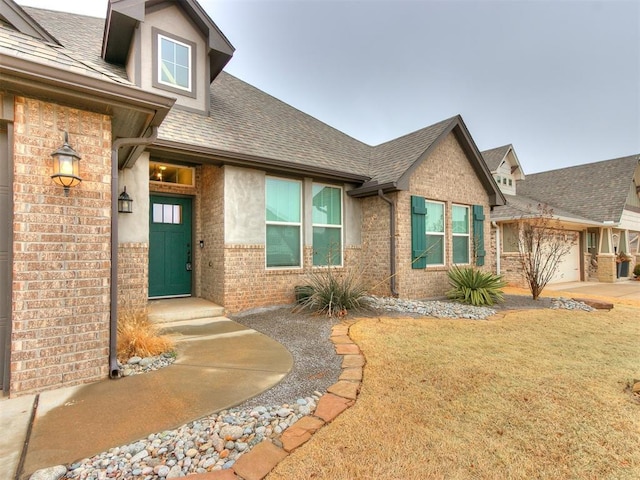 view of exterior entry with a garage and a lawn