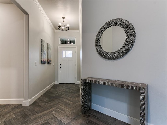 foyer entrance with ornamental molding, a notable chandelier, and dark parquet floors