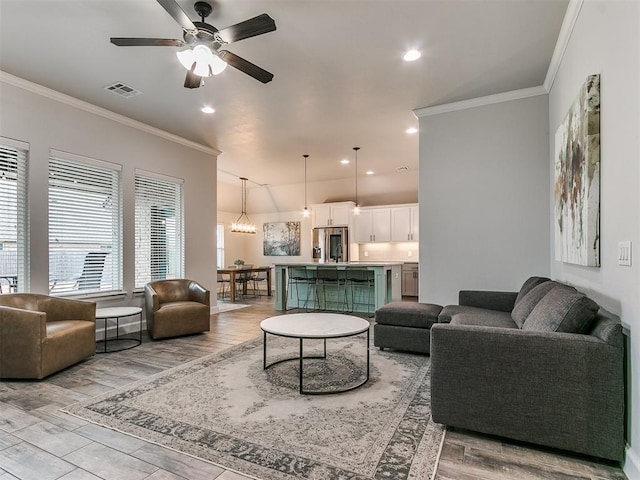 living room featuring crown molding, ceiling fan, and light wood-type flooring