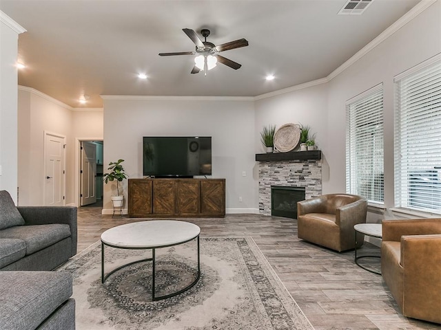 living room with ceiling fan, ornamental molding, a fireplace, and light hardwood / wood-style flooring