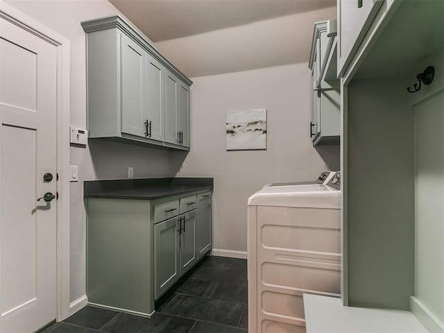 laundry area featuring cabinets, dark tile patterned flooring, and washing machine and clothes dryer