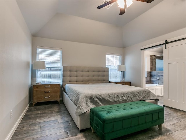 bedroom featuring vaulted ceiling, a barn door, ensuite bathroom, and ceiling fan