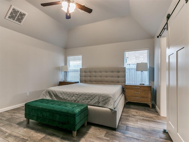 bedroom with ceiling fan, lofted ceiling, and a barn door