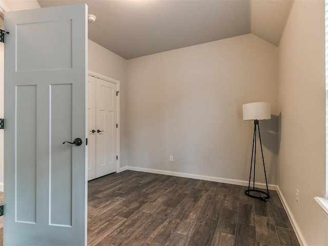 spare room featuring lofted ceiling and dark hardwood / wood-style floors