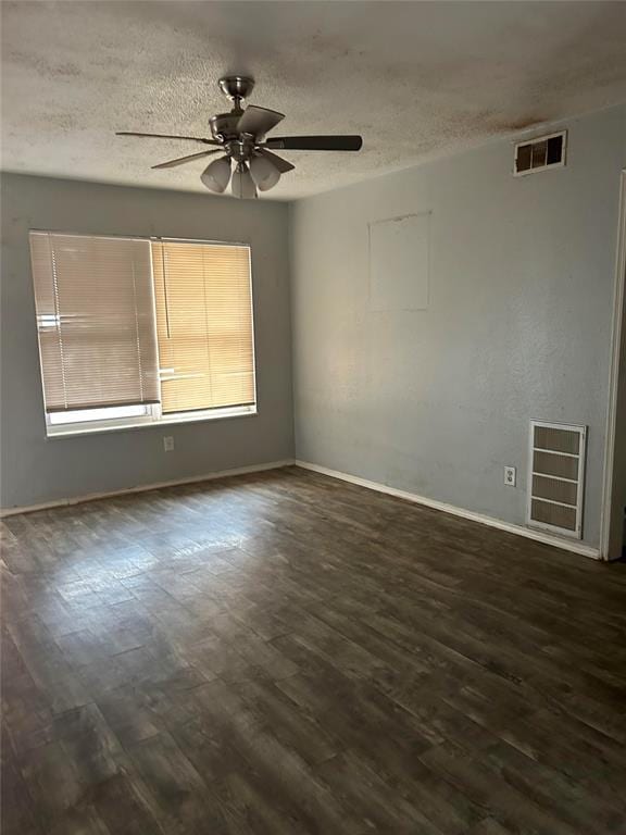 empty room featuring ceiling fan, dark wood-type flooring, and a textured ceiling