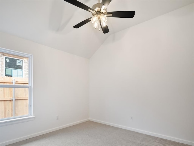 spare room featuring light colored carpet, vaulted ceiling, baseboards, and ceiling fan