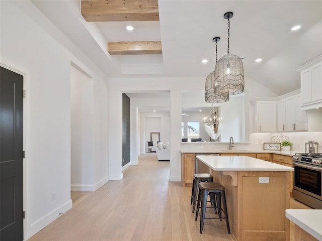 kitchen featuring a breakfast bar area, a kitchen island, a sink, light countertops, and gas stove