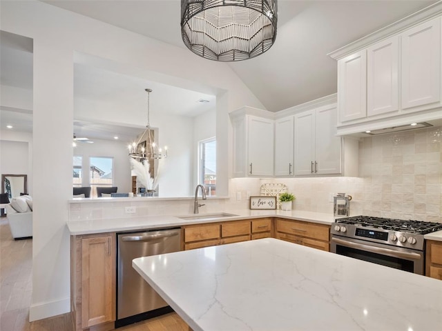 kitchen with a sink, white cabinets, appliances with stainless steel finishes, decorative backsplash, and light stone countertops
