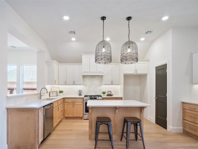 kitchen with stainless steel appliances, a sink, visible vents, and decorative backsplash