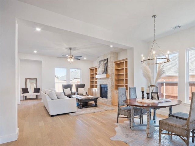 living area with recessed lighting, light wood-style flooring, visible vents, and a stone fireplace