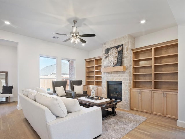 living area with visible vents, ceiling fan, a stone fireplace, light wood-style floors, and recessed lighting