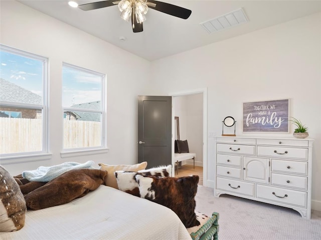 bedroom featuring ceiling fan, visible vents, baseboards, and light colored carpet