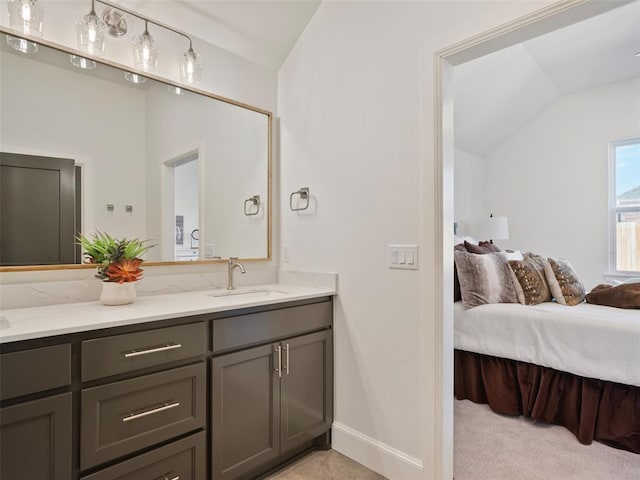 bathroom with ensuite bath, baseboards, vaulted ceiling, and vanity