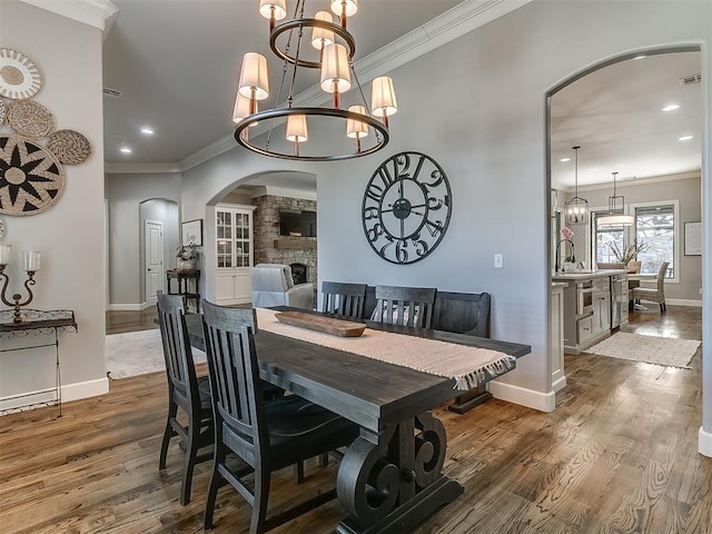 dining space featuring dark hardwood / wood-style floors, ornamental molding, sink, and a fireplace