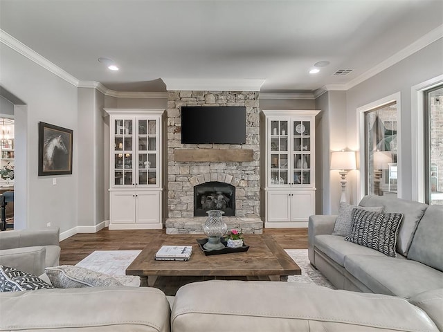 living room with hardwood / wood-style flooring, a stone fireplace, and ornamental molding