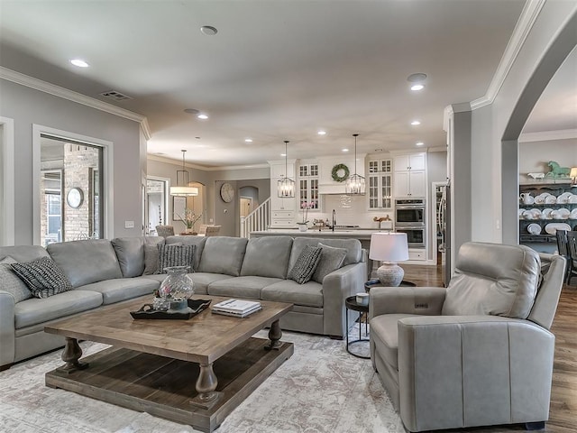 living room featuring sink, a notable chandelier, ornamental molding, and light hardwood / wood-style floors