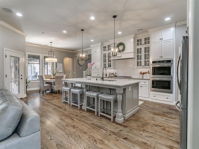 kitchen featuring pendant lighting, sink, appliances with stainless steel finishes, an island with sink, and white cabinets