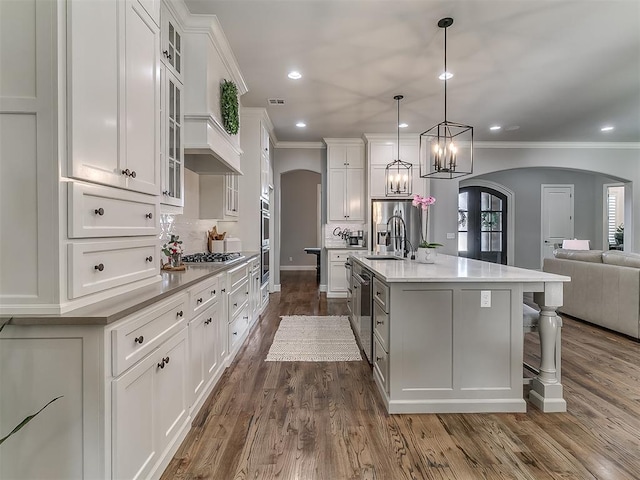 kitchen featuring pendant lighting, white cabinets, appliances with stainless steel finishes, and a large island with sink