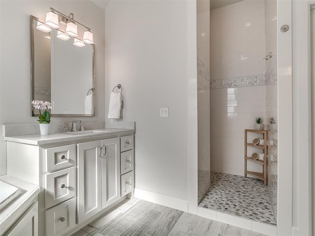 bathroom featuring tiled shower and vanity