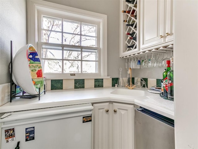 interior space featuring white cabinetry, dishwashing machine, and sink