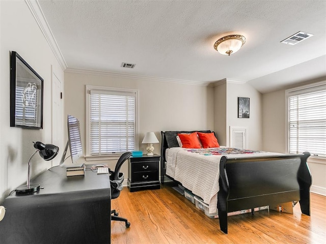 bedroom with ornamental molding, lofted ceiling, a textured ceiling, and light hardwood / wood-style floors