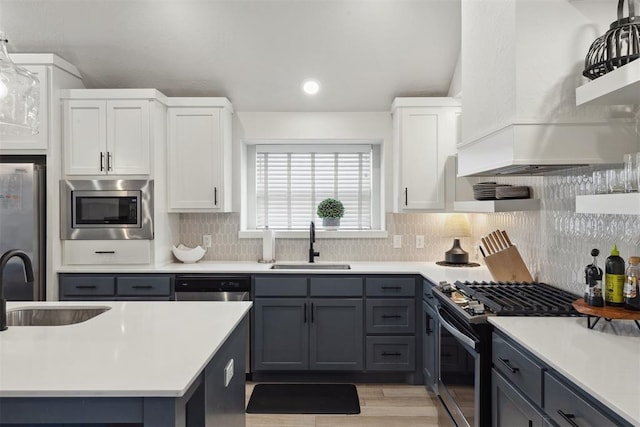 kitchen featuring white cabinetry, appliances with stainless steel finishes, sink, and premium range hood