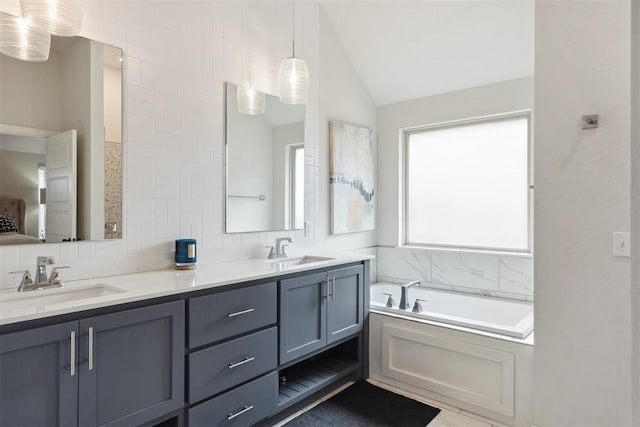 bathroom featuring vanity, a bath, vaulted ceiling, and tasteful backsplash