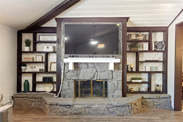 living room with a stone fireplace, wood-type flooring, and vaulted ceiling