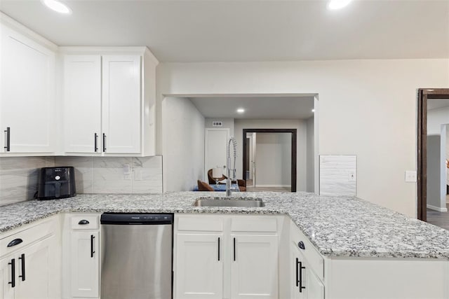 kitchen featuring tasteful backsplash, white cabinetry, sink, stainless steel dishwasher, and kitchen peninsula