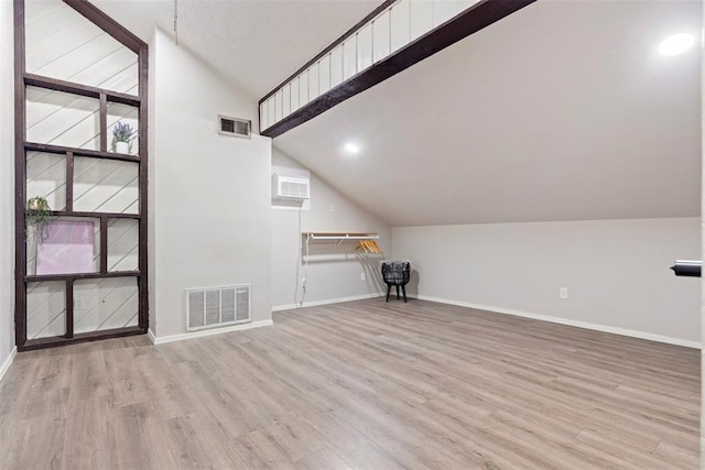 bonus room featuring vaulted ceiling, a wall mounted air conditioner, and light hardwood / wood-style floors