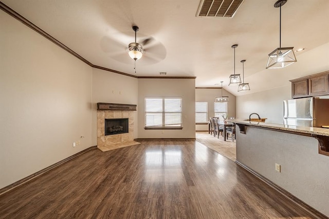 unfurnished living room with vaulted ceiling, ornamental molding, dark hardwood / wood-style floors, and a tile fireplace