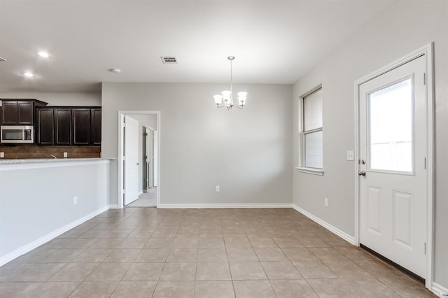 unfurnished dining area with light tile patterned floors and a notable chandelier