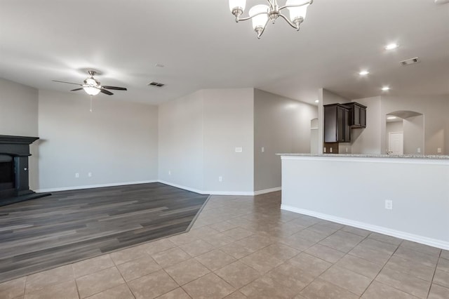 unfurnished living room with tile patterned flooring and ceiling fan with notable chandelier