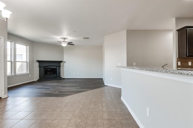 unfurnished living room featuring light tile patterned floors and ceiling fan