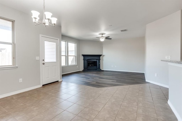 unfurnished living room featuring light tile patterned floors and ceiling fan with notable chandelier