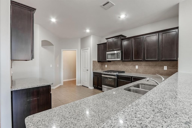 kitchen with sink, light stone countertops, and appliances with stainless steel finishes