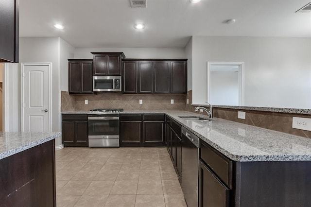 kitchen featuring light tile patterned flooring, sink, appliances with stainless steel finishes, light stone countertops, and decorative backsplash