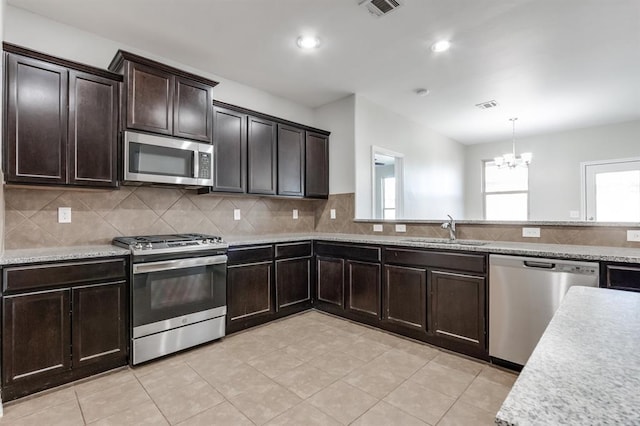 kitchen with appliances with stainless steel finishes, decorative light fixtures, tasteful backsplash, sink, and dark brown cabinetry