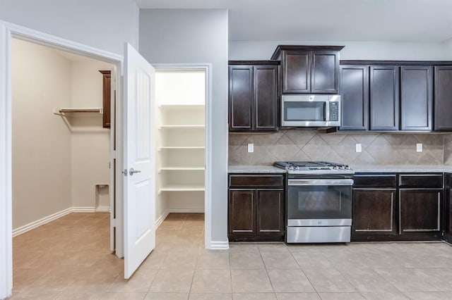 kitchen with tasteful backsplash, light tile patterned floors, dark brown cabinets, and appliances with stainless steel finishes