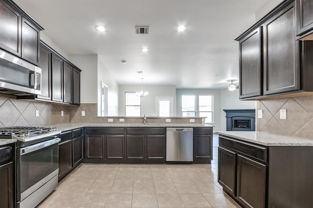 kitchen with pendant lighting, stainless steel appliances, kitchen peninsula, and sink