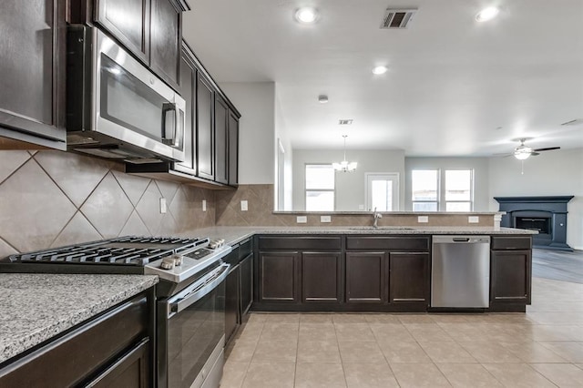 kitchen featuring appliances with stainless steel finishes, ceiling fan with notable chandelier, sink, backsplash, and hanging light fixtures