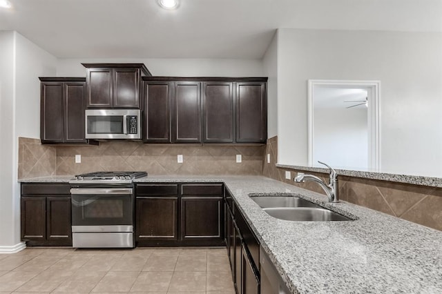 kitchen with appliances with stainless steel finishes, sink, decorative backsplash, light tile patterned floors, and dark brown cabinetry