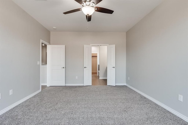 unfurnished bedroom featuring a walk in closet, light colored carpet, and ceiling fan