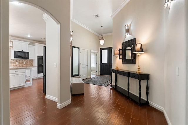 entrance foyer with dark wood-type flooring, ornamental molding, and a high ceiling